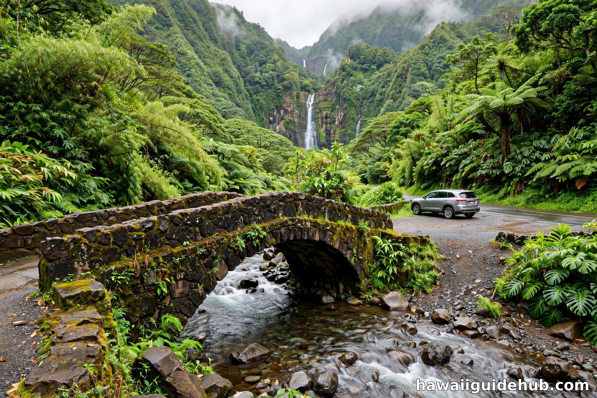 Small bridge over Hanawi Stream on the Road to Hana with the waterfall visible against rainforest mountains