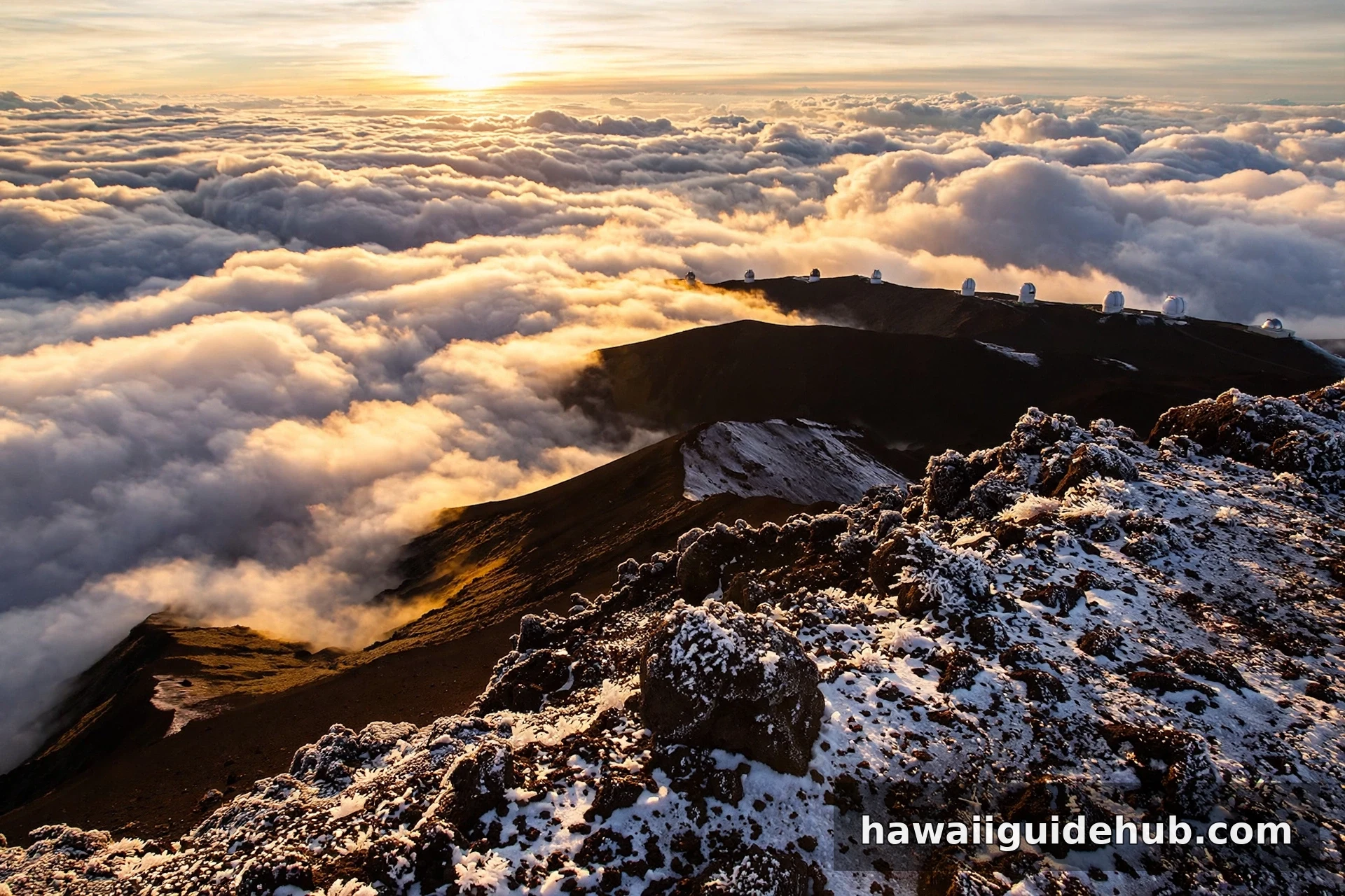 Snow-dusted summit of Mauna Kea rising above a sea of clouds at sunrise in Hawaii