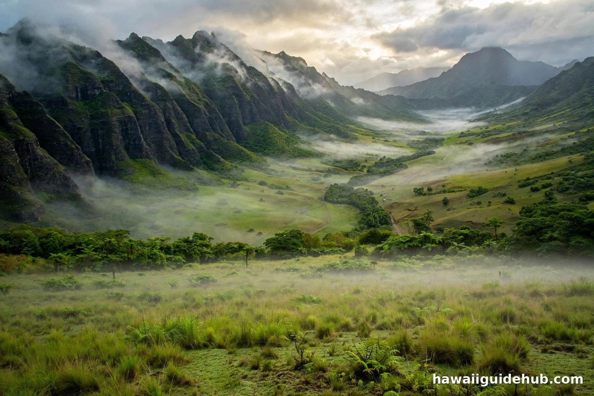 Aerial view of Ka'a'awa Valley at Kualoa Ranch, Oahu, with misty jagged Ko'olau mountain ridges and green valley floor