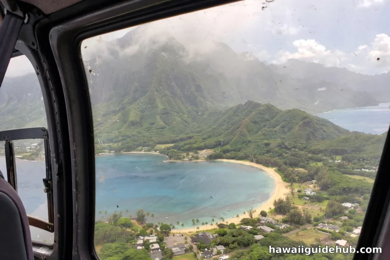Crescent of Kahana Bay seen from a helicopter with the green Koolau mountains behind on Oahu windward coast