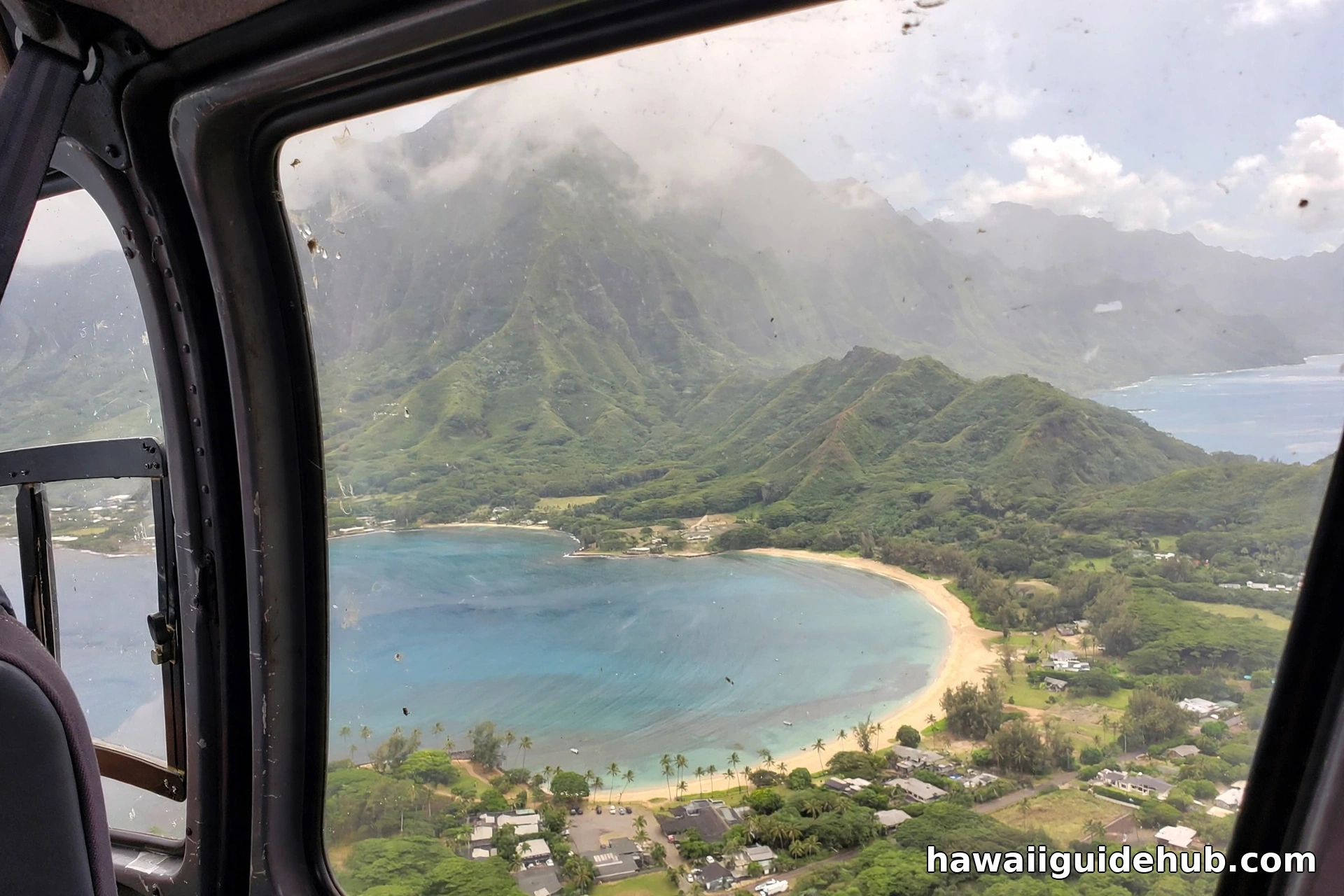 Crescent of Kahana Bay seen from a helicopter with the green Koolau mountains behind on Oahu windward coast