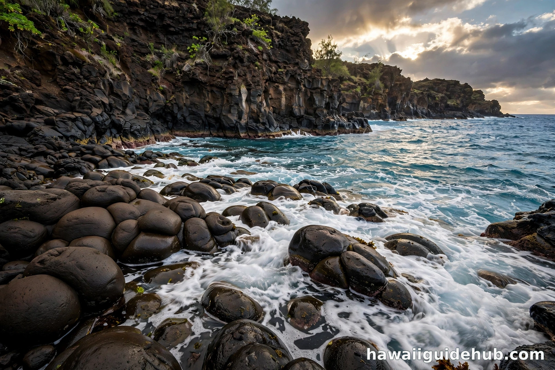 Rounded pillow lava rocks along a rugged Hawaiian volcanic coastline