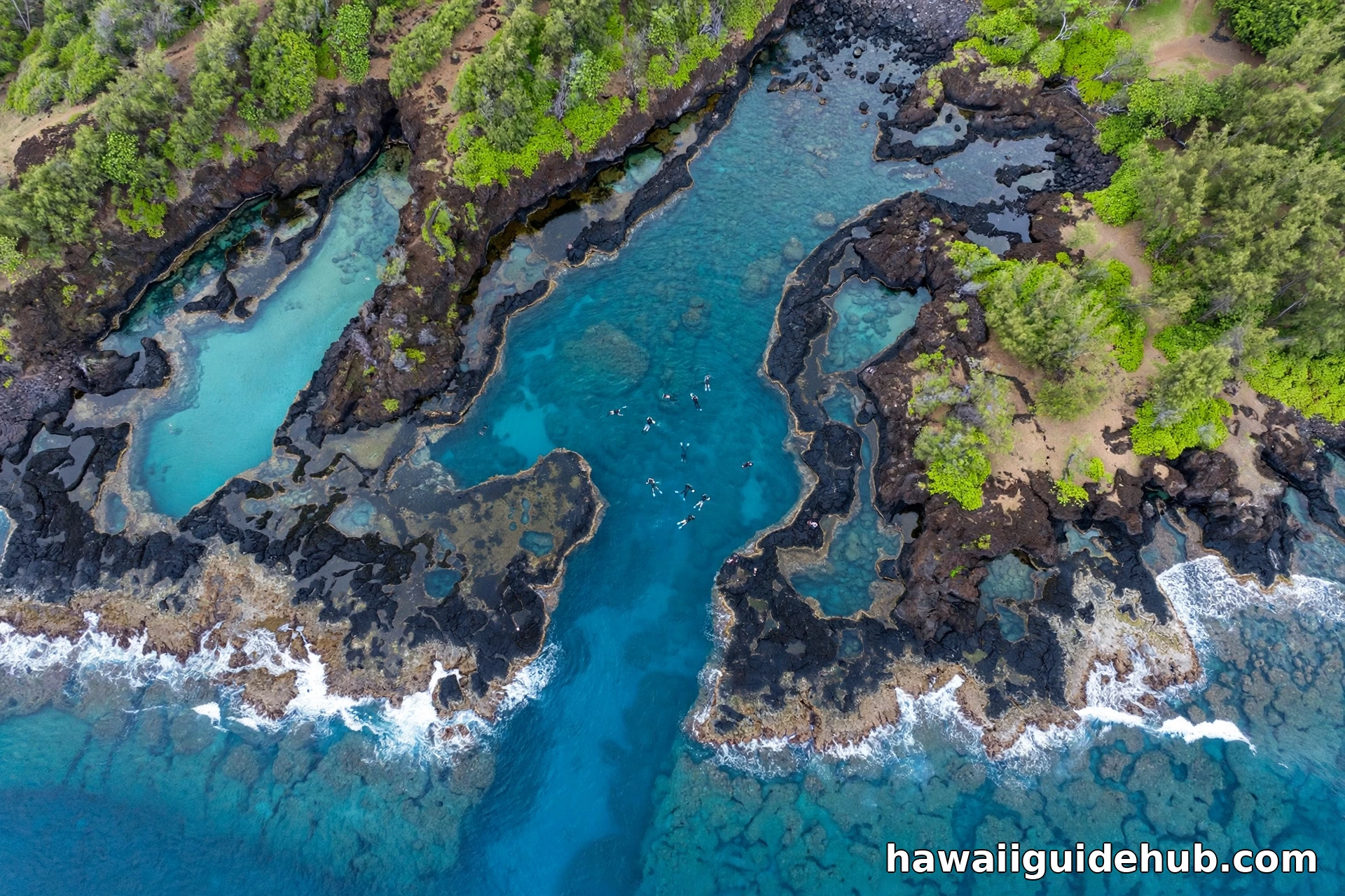 Aerial view of Shark's Cove at Pupukea Beach Park with lava rock tide pools and snorkelers in turquoise water