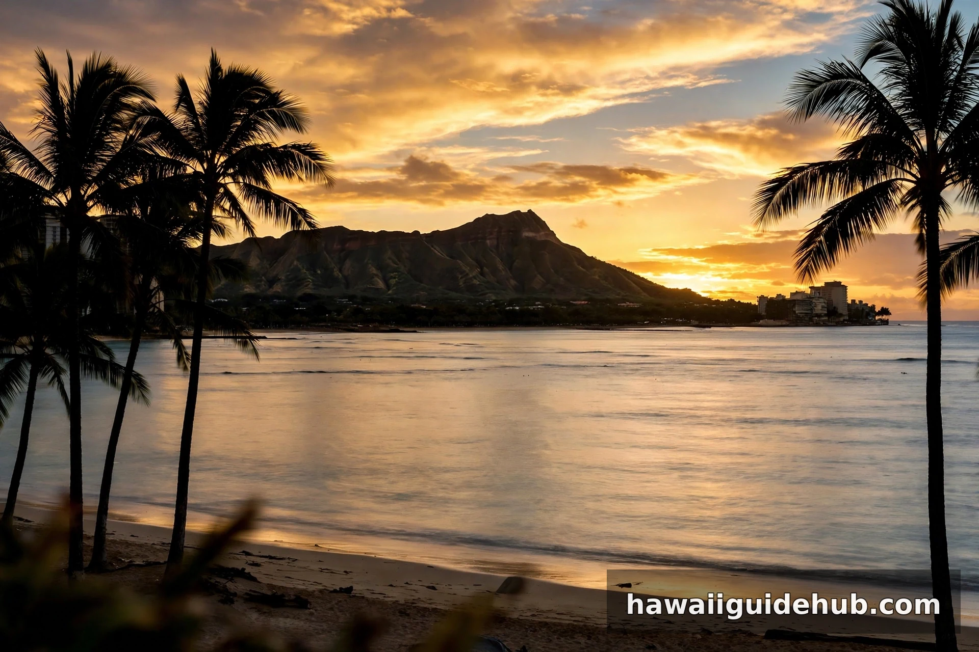 Sunrise over Diamond Head crater viewed from Waikiki Beach in Honolulu, with palm tree silhouettes and golden morning sky