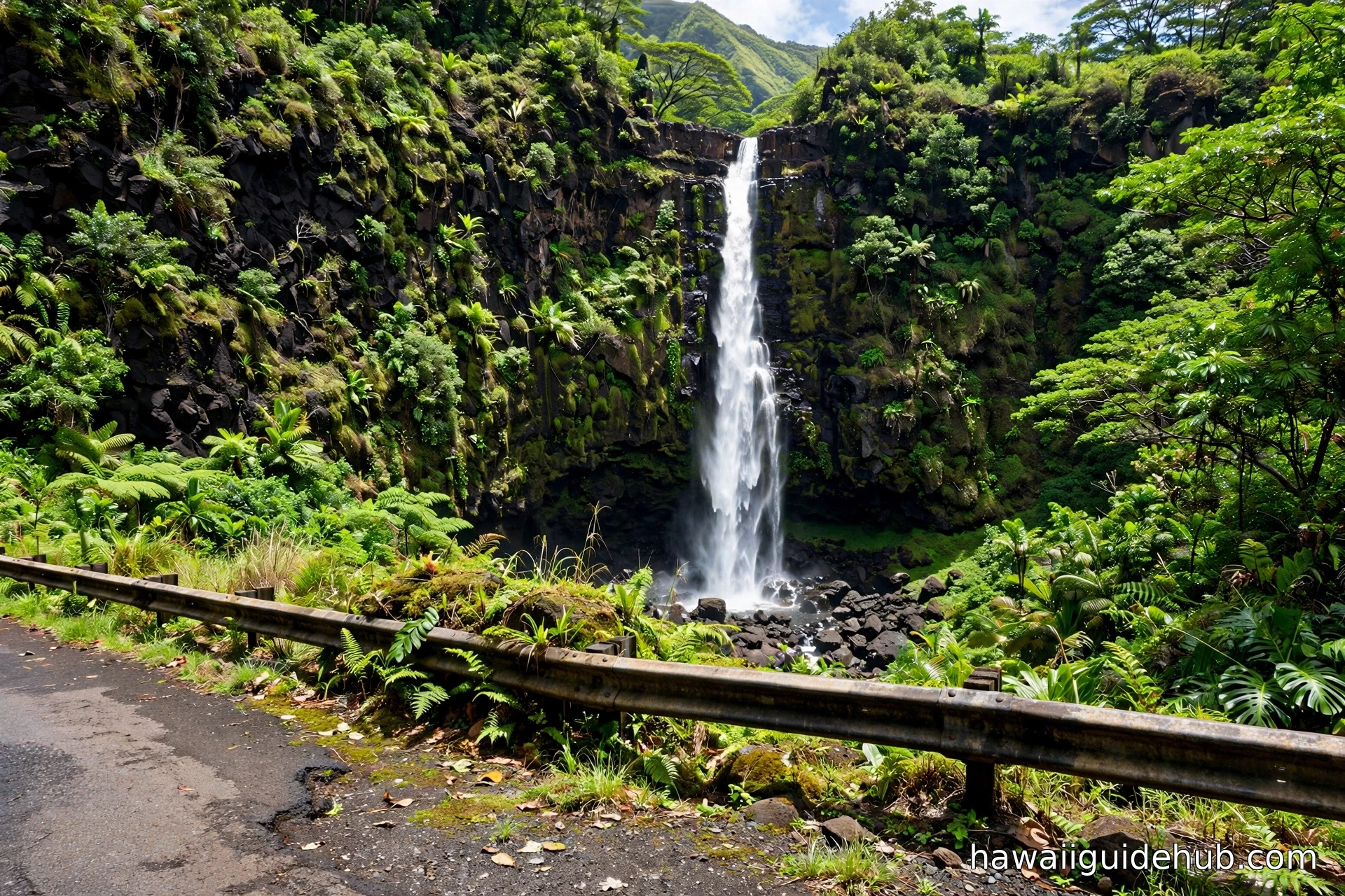 Wailua Falls plunging 80 feet down a lush volcanic cliff face beside the Hana Highway, viewed from the roadside pullout