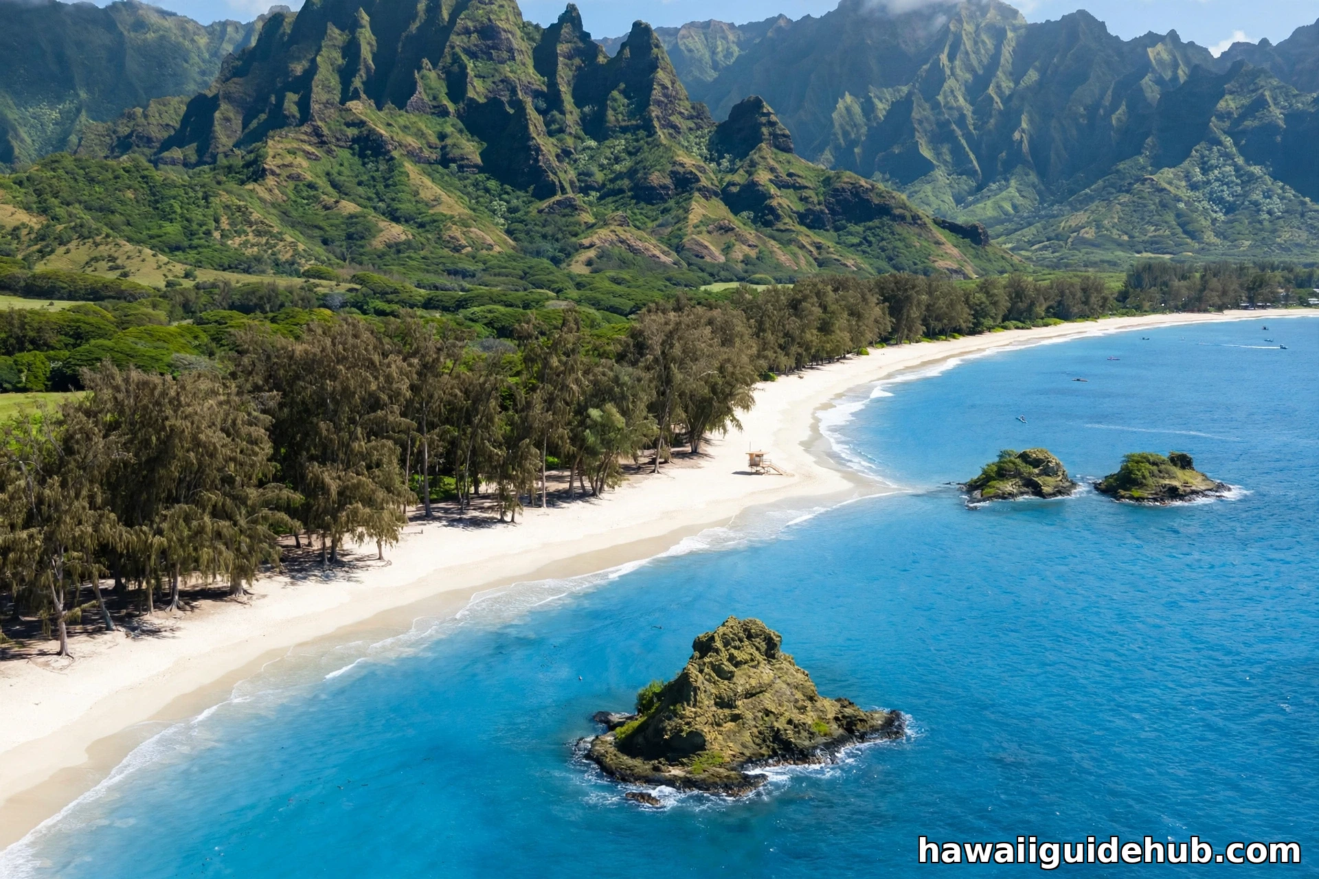 Aerial view of Waimānalo Beach with white sand, turquoise water, ironwood trees, the Koʻolau mountains, and offshore islets